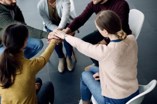 Participants-therapie-groupe-reunissant-mains-dans-unite-lors-seance-au-centre-medical